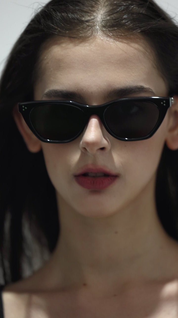 Walking model wearing Dex in black cat-eye stylish Sunglasses from Mercury Retrograde Burr Puzzle Collection 