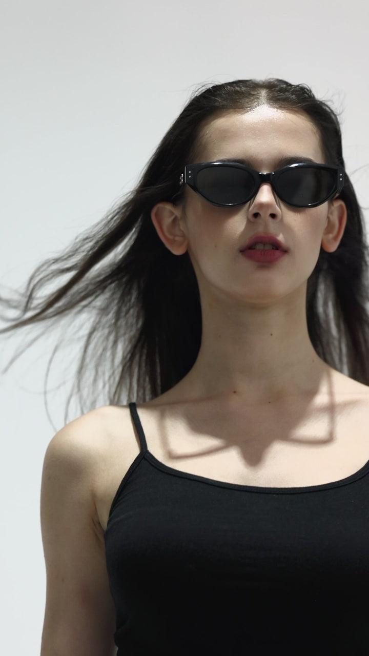 Walking female model wearing her Burr Puzzle’s Symphony in black cat-eye Designer Sunglasses from Mercury Retrograde  