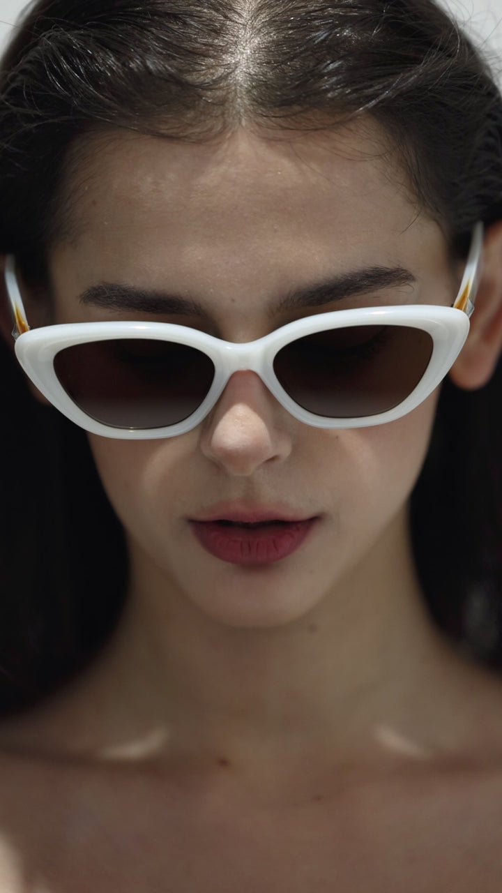 Close-up of walking model wearing Virgo in white cat-eye Designer Sunglasses from Mercury Retrograde Galaxy Collection 