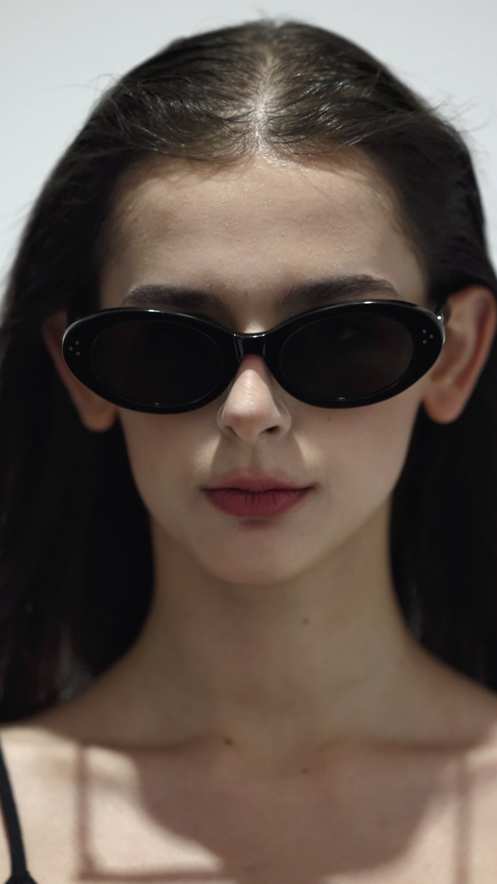 Close-up of walking female model wearing her  Wave in black round Designer Sunglasses with UV protection from Mercury Retrograde Burr Puzzle Collection 