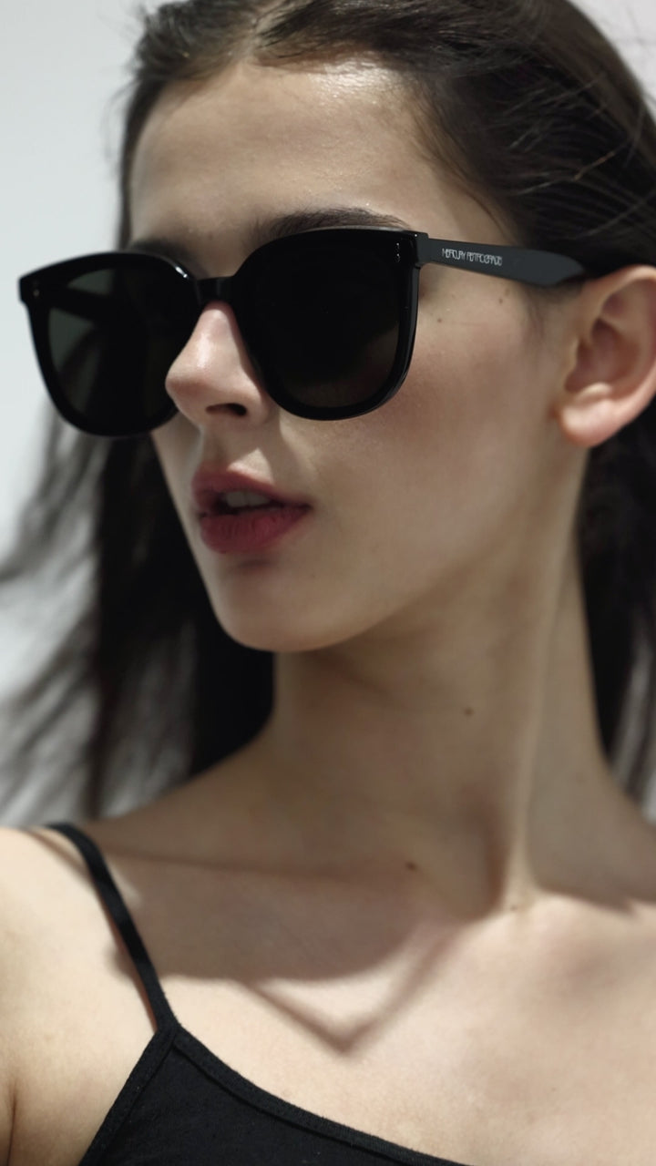 Close-up of walking model wearing Burr Puzzle’s Manta in black  Designer square Sunglasses from Mercury Retrograde