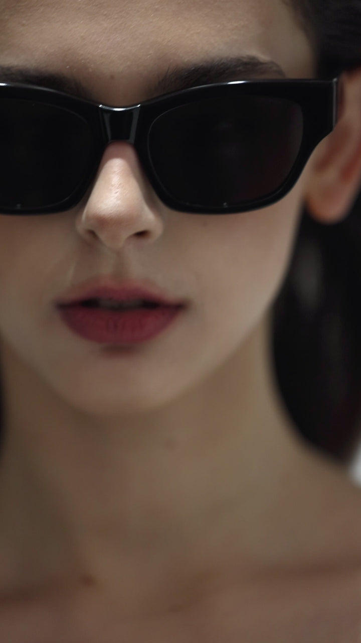 Close-up of walking female model wearing her Daydream’s Muse in black square fashion Sunglasses from Mercury Retrograde  